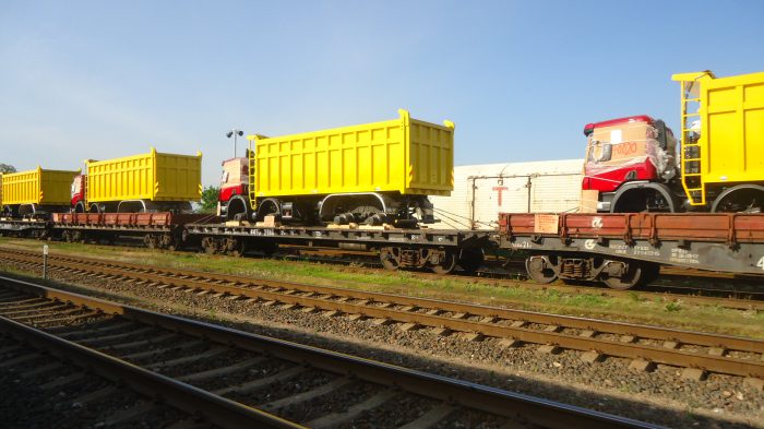 rote und gelbe LKWs auf einem Zug